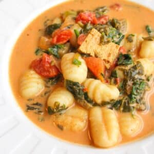 A bowl of gnocchi soup in a creamy coconut broth with tofu and kale.