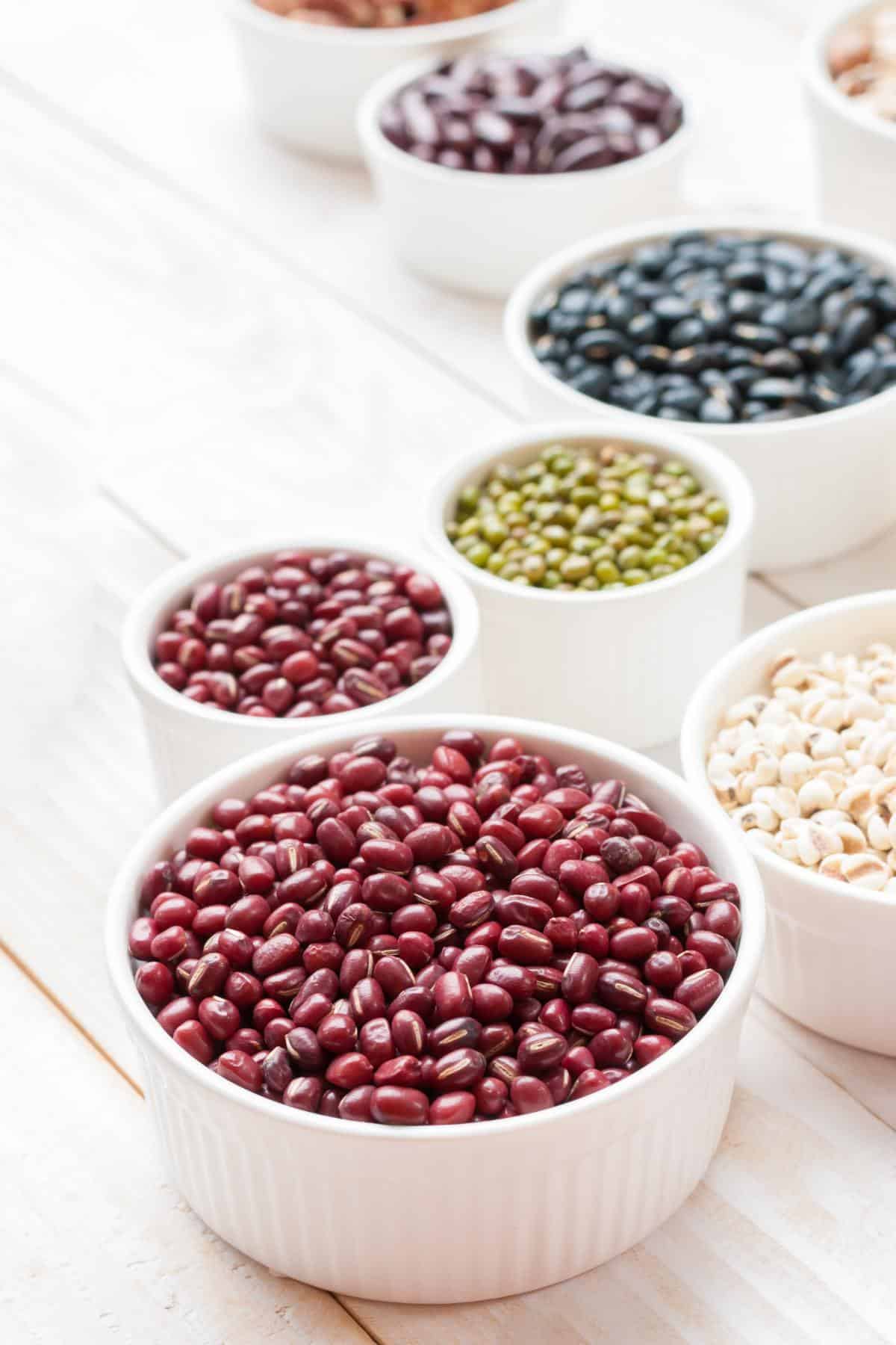 Small white bowls filled with a variety of dried beans.