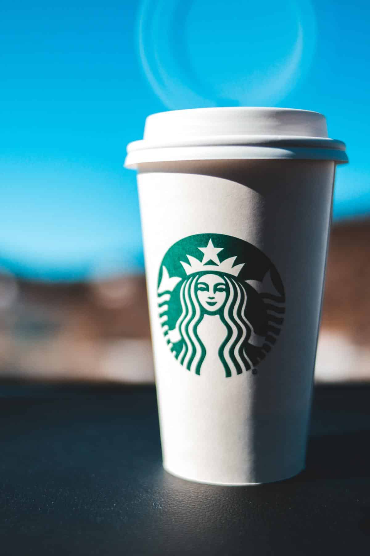 A Starbuck's to-go mug sitting on a car dash board.