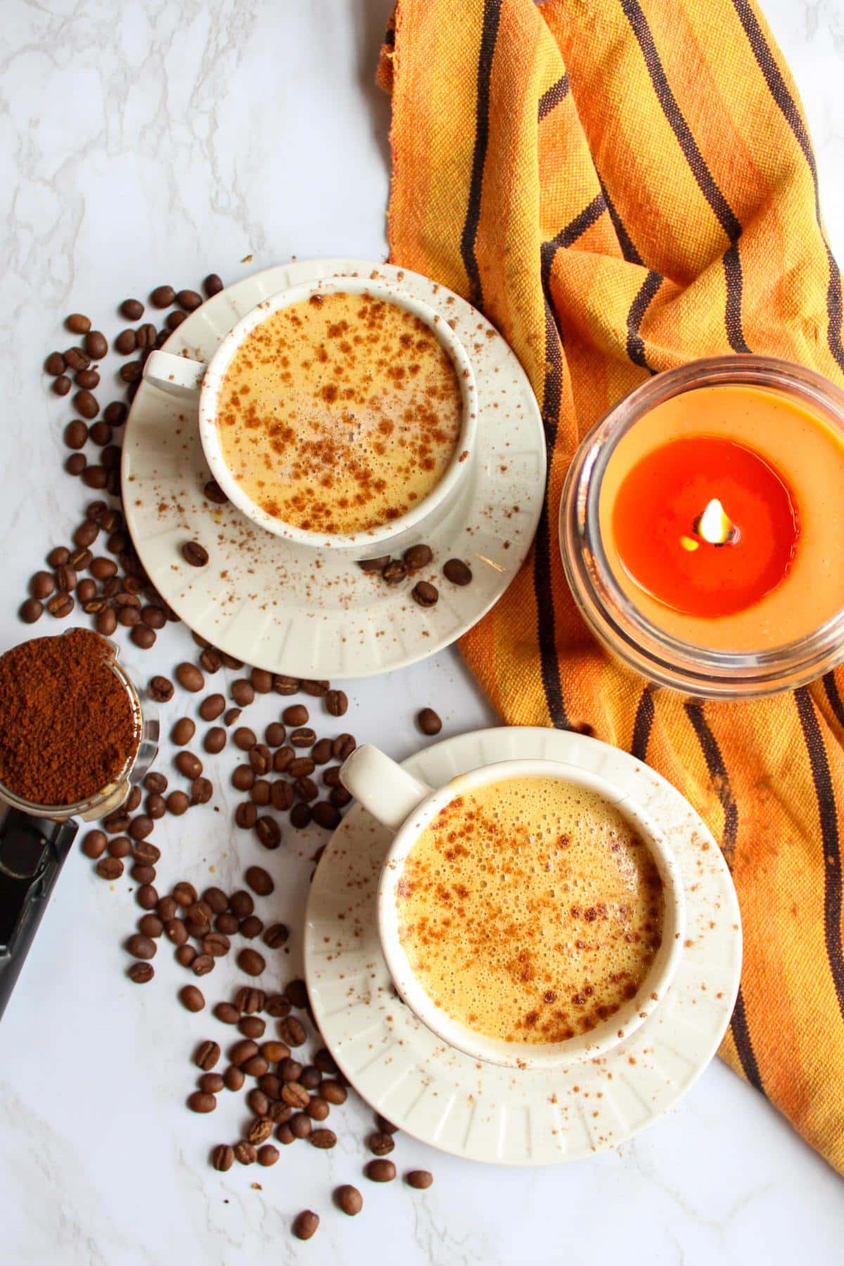 Overhead view of two mugs of vegan pumpkin spice latte on a table.