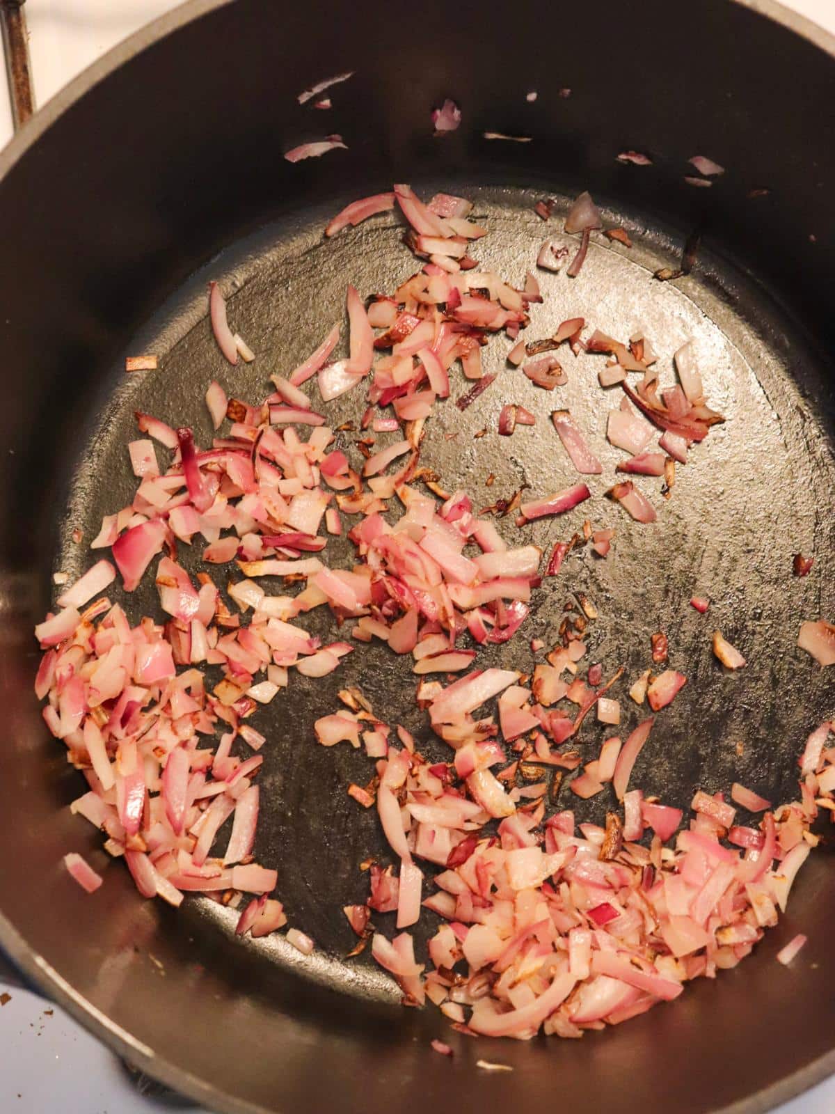 Red onions sautéing in a large pot on the stove.