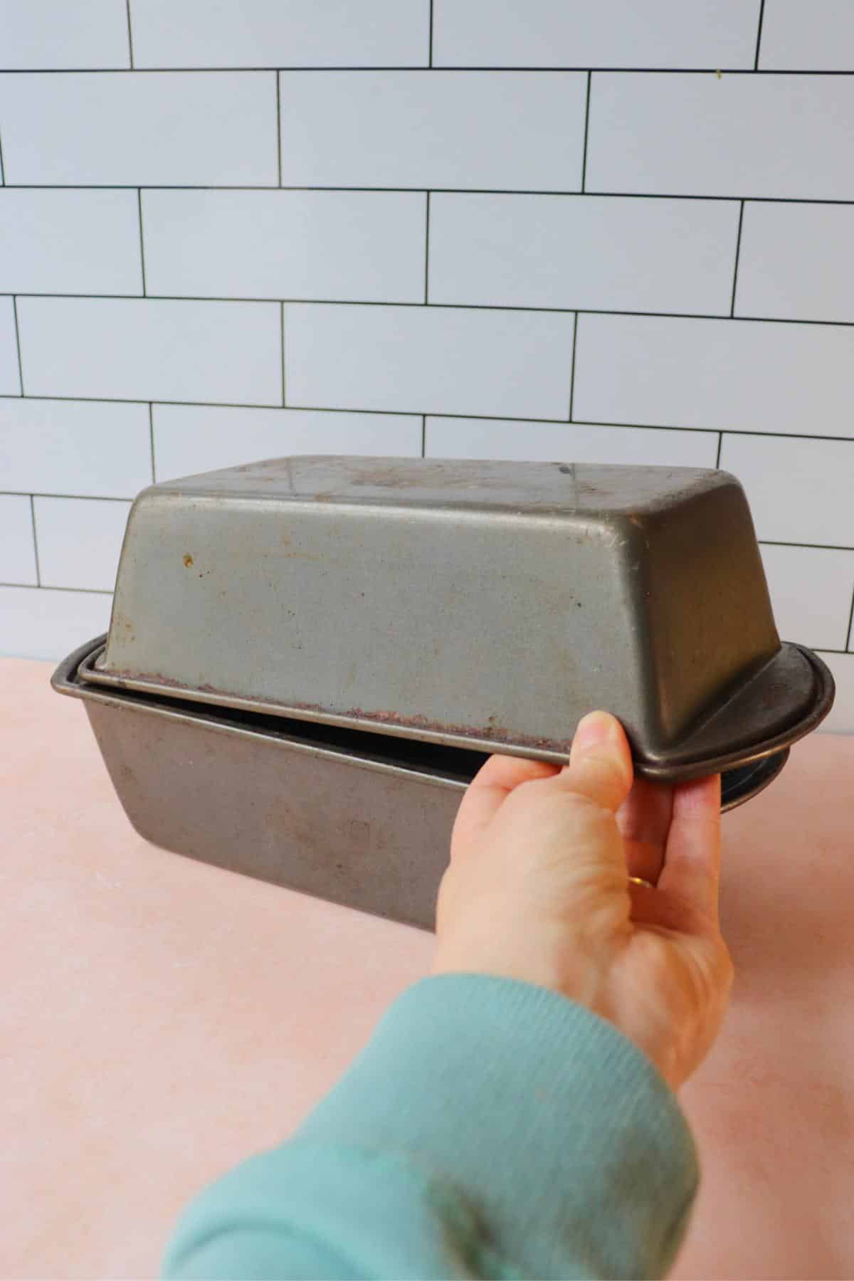 Bread dough in a bread pan with another bread pan flipped upside down on it to create a lid.