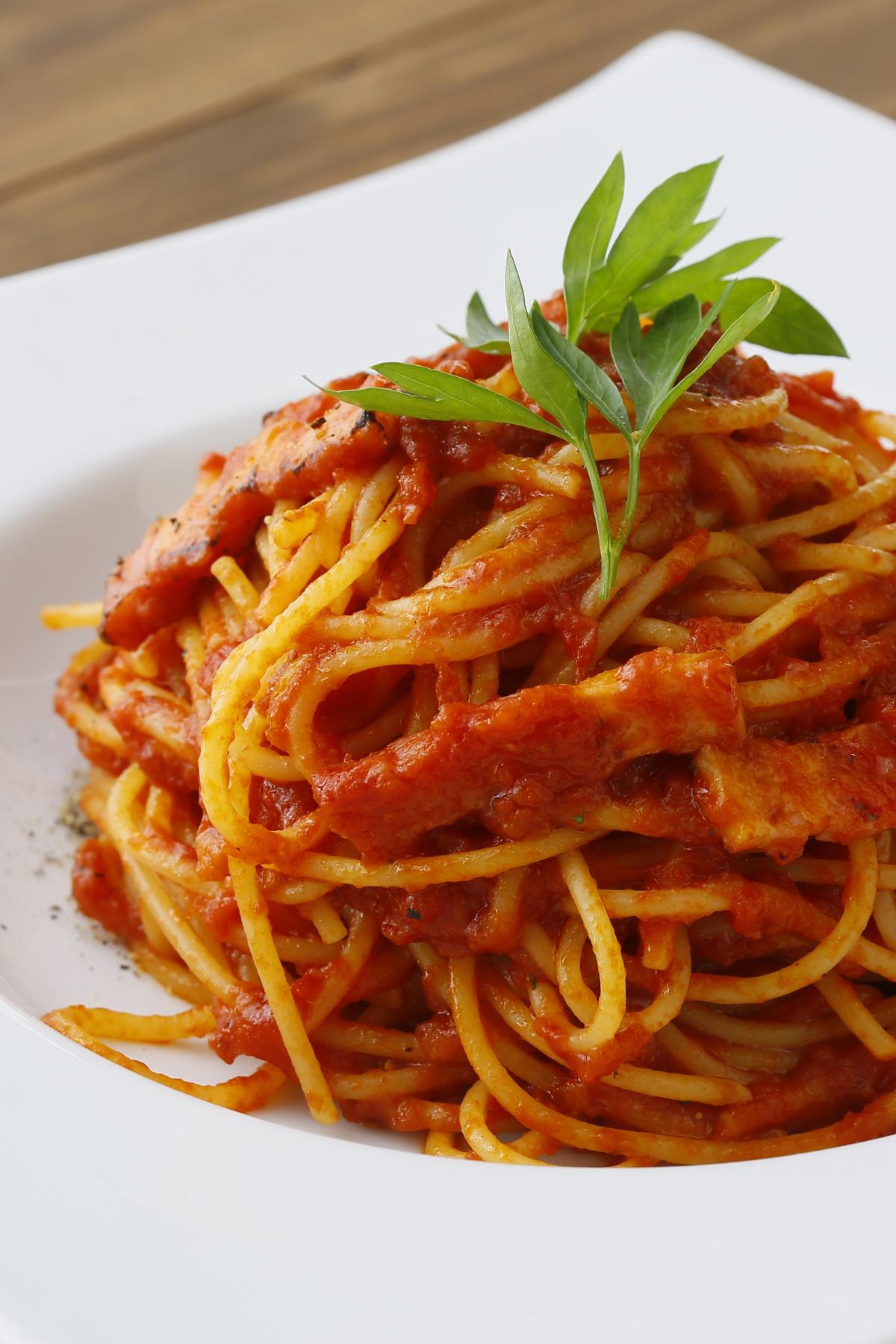 Plate of spaghetti with tomato sauce topped with a basil leaf. 