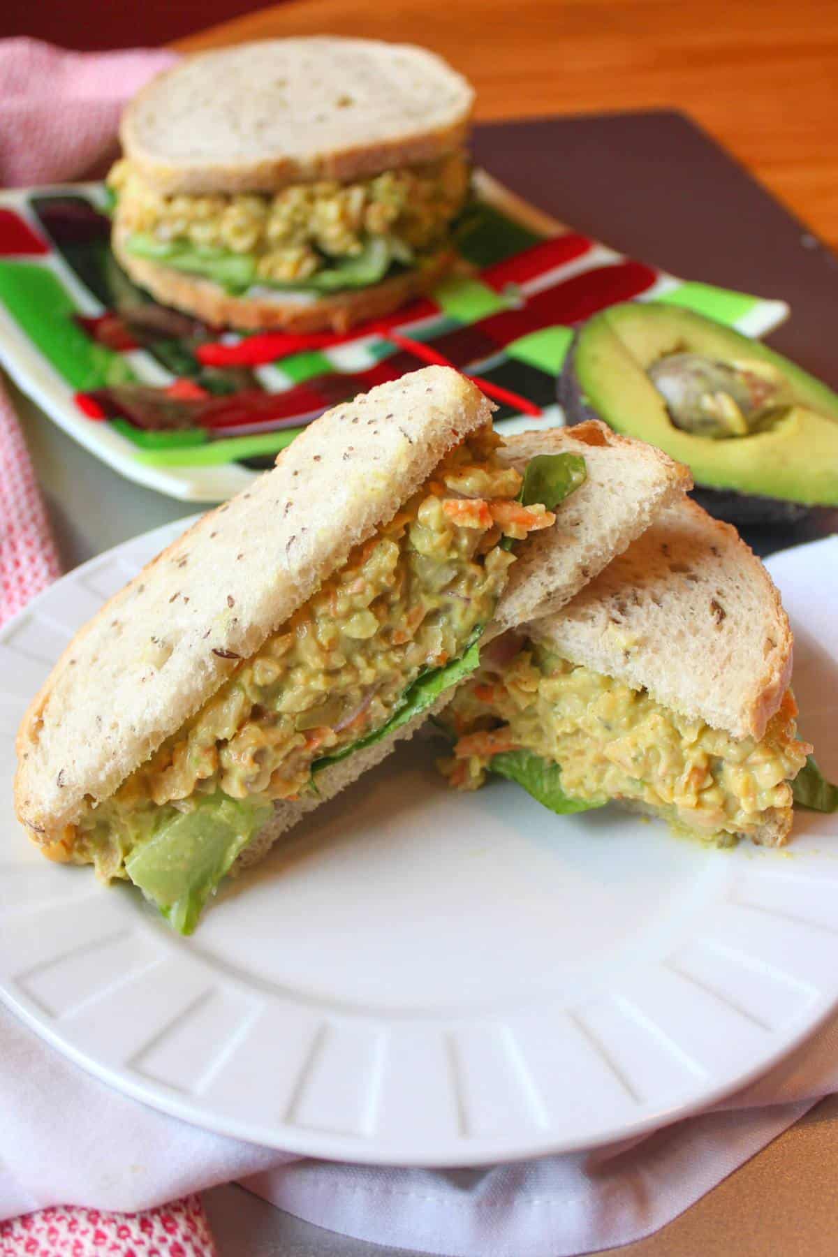 Chickpea salad sandwich, cut in half, on a white plate.