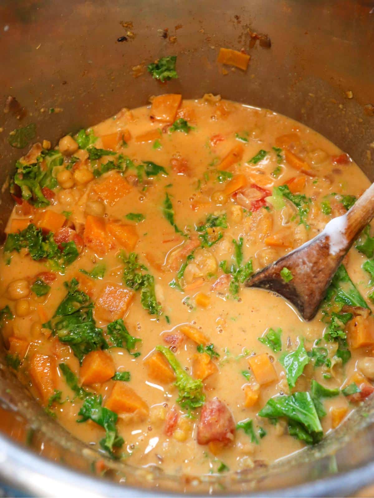 Sweet potato coconut curry in an instant pot with a wooden spoon.