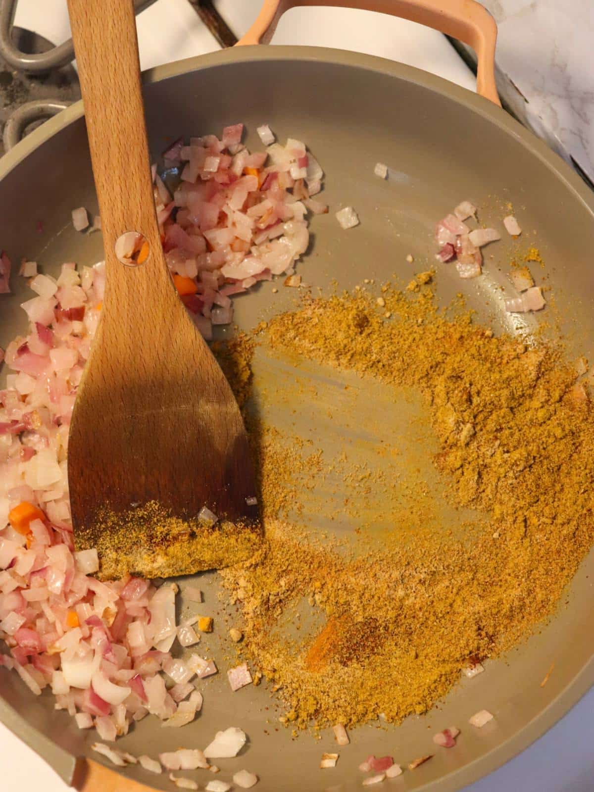 Curry spices and red onions in a saute pan.