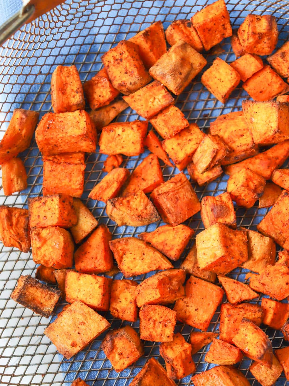 Seasoned sweet potato cubes in an air fryer basket.