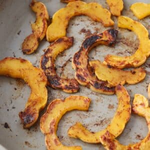 Sautéed delicata squash after being cooked in a pan on the stove.