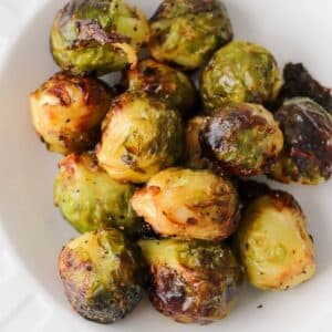 Frozen brussels sprouts in a white bowl that have been cooked in an air fryer.