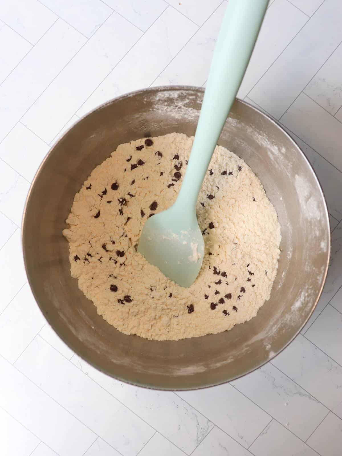 Dry ingredients for vegan banana muffins in a small mixing bowl with a rubber spatula.