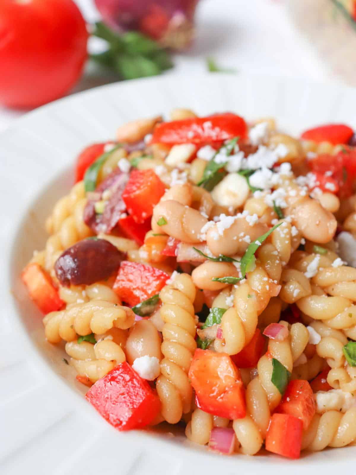 Balsamic pasta salad in a white bowl topped with fresh basil.