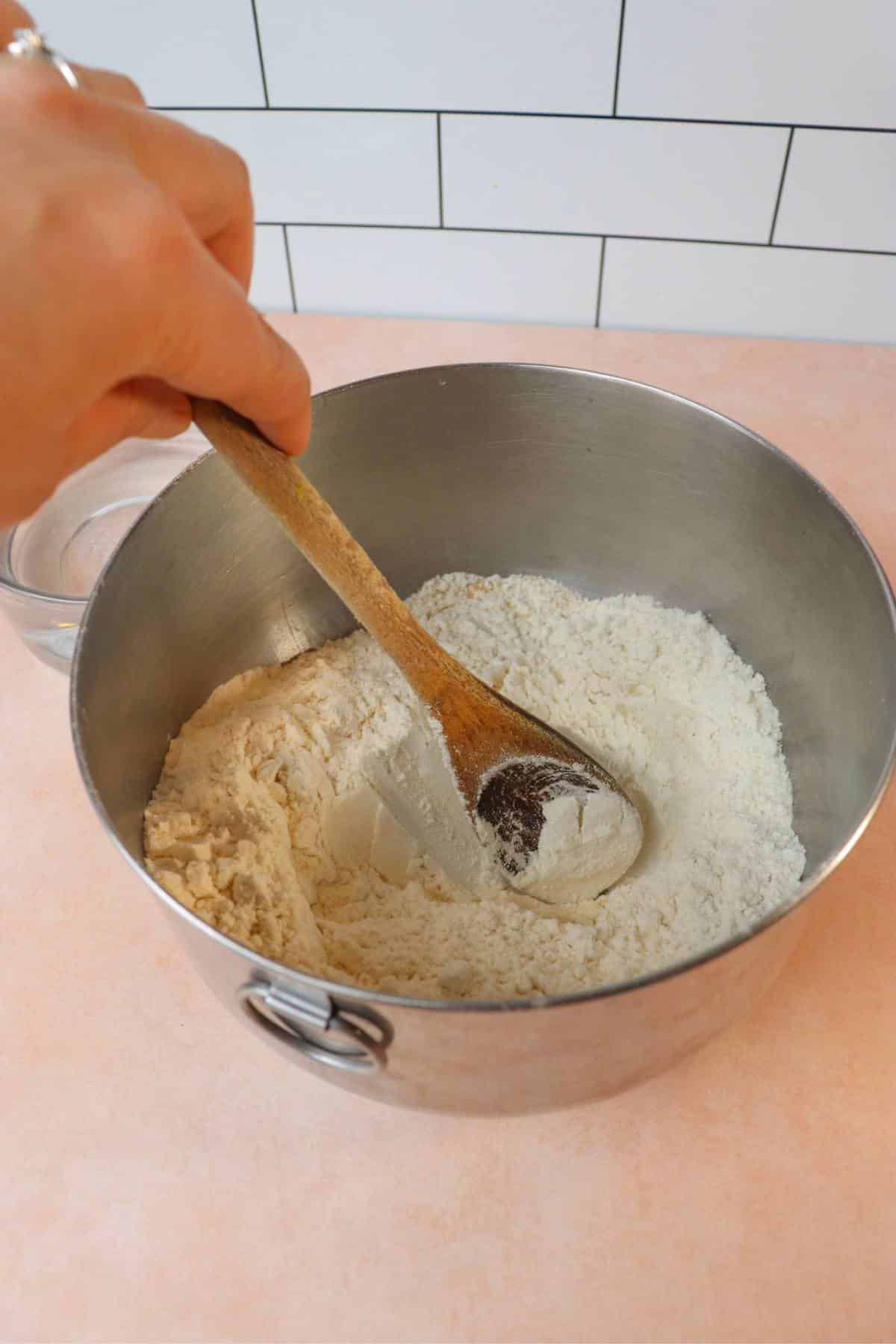 Dry ingredients for homemade bread being mixed together in a mixing bowl.
