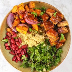 Quinoa tofu bowl with kale kidney beans and sweet potatoes on a counter.