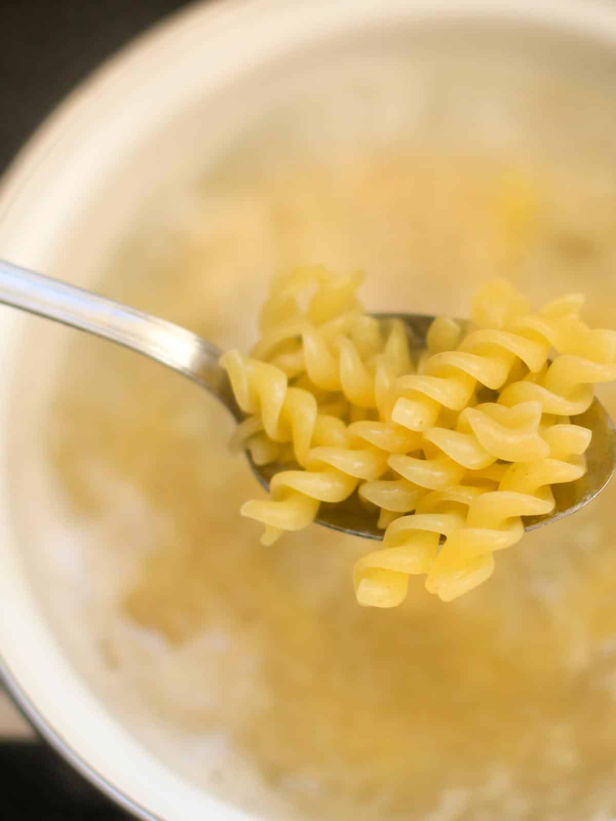 Rotini pasta boiling in a pot on the stove.