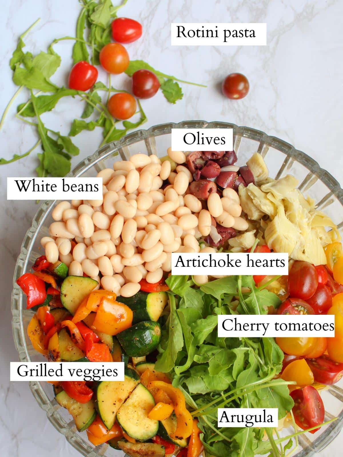 Ingredients for grilled veggie pasta salad arranged in a large glass serving bowl.