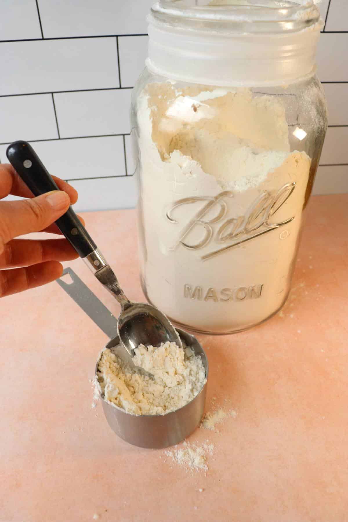 Flour being spooned into a measuring cup.