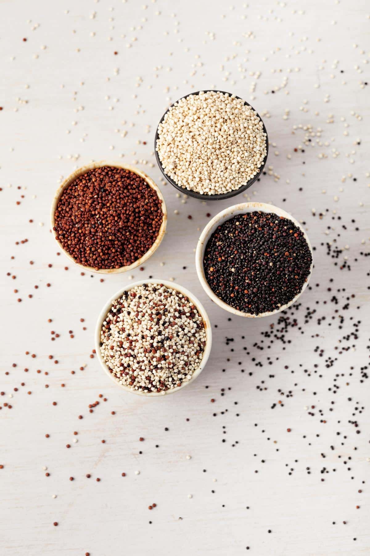 Small bowls of white, red, black and mixed quinoa on a table. 