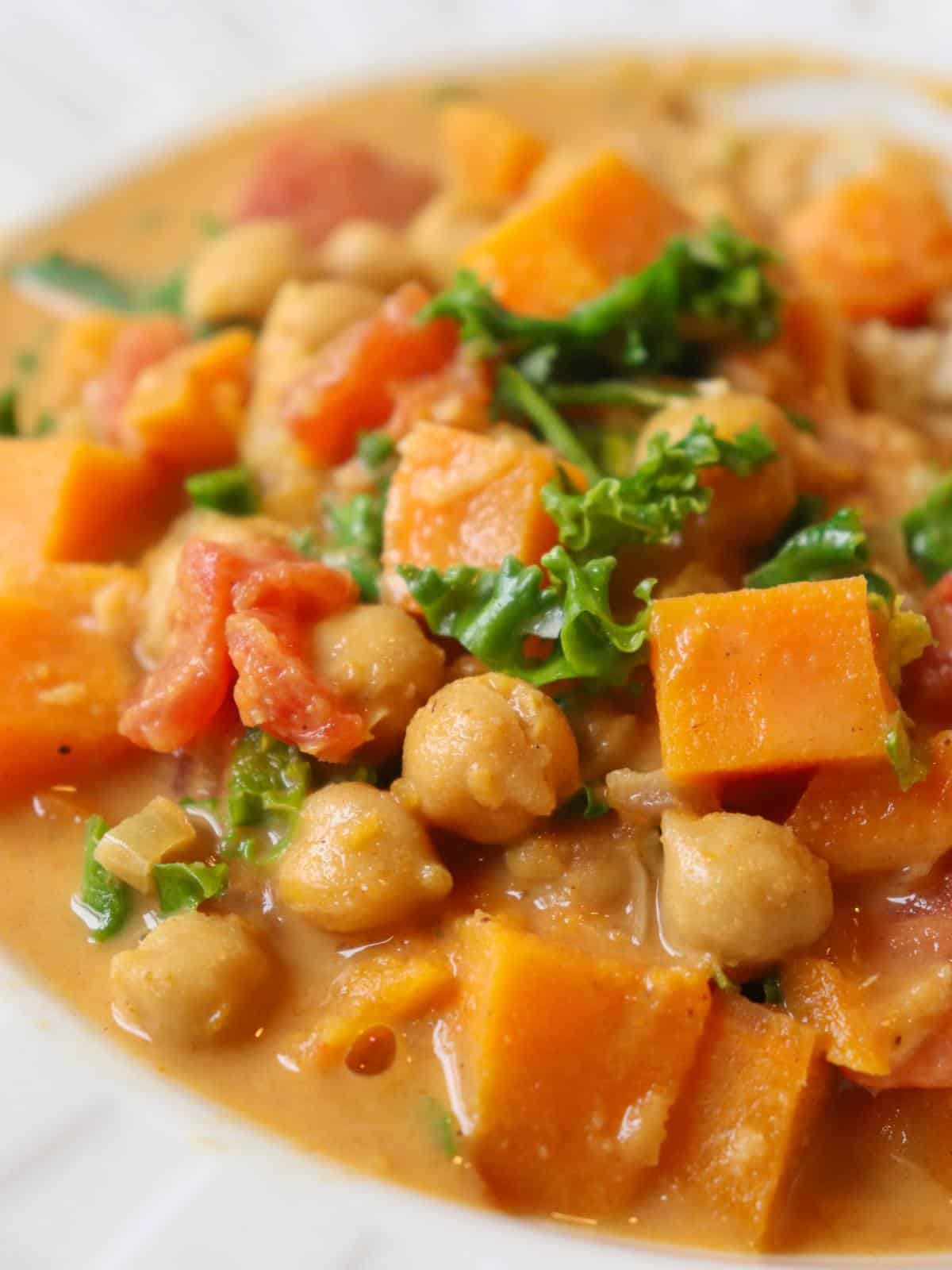 Sweet potato chickpea curry in a white bowl with kale.