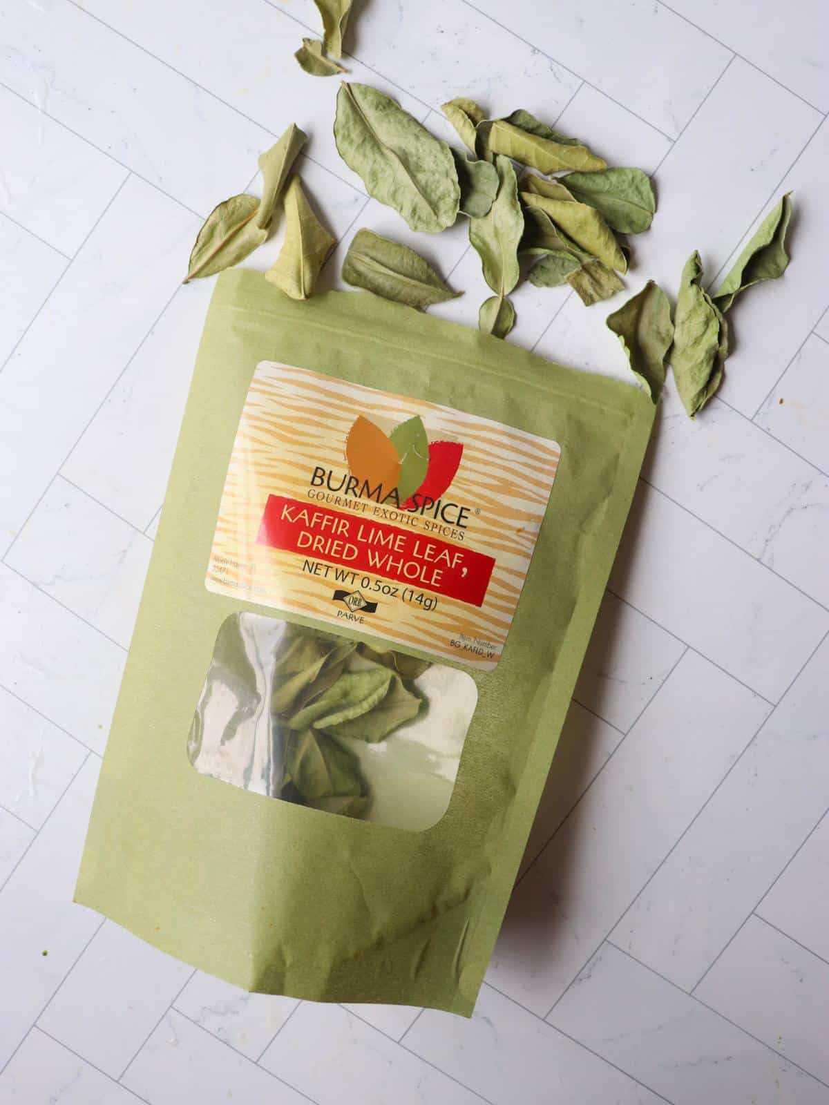 Kaffir lime leaves in a green bag on a kitchen counter.