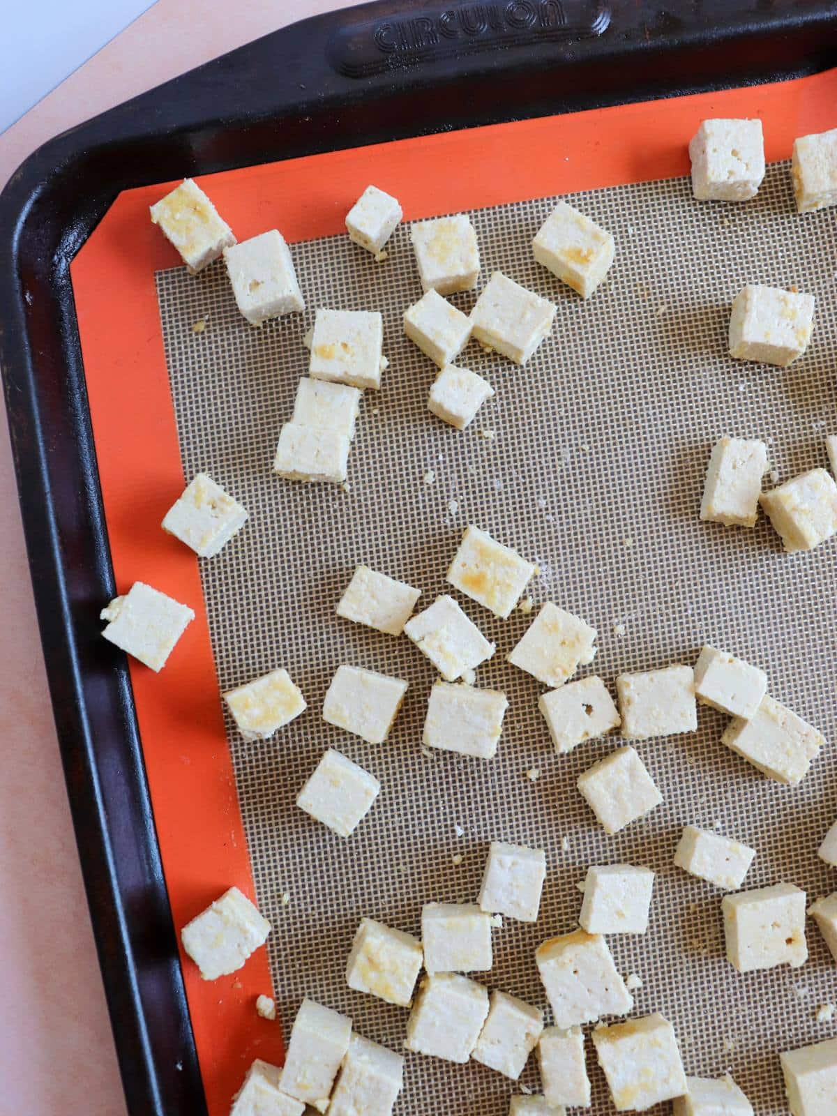 Tofu cubes on a lined baking sheet.