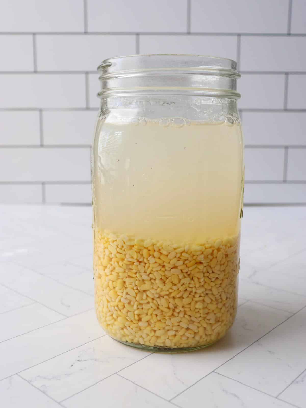 Yellow split peas soaking in a large glass mason jar.