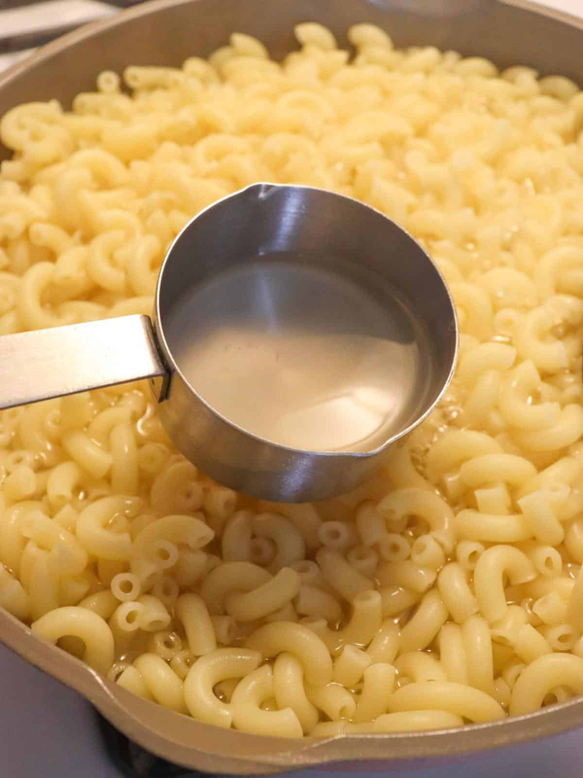 Macaroni noodles being cooked in a pan.