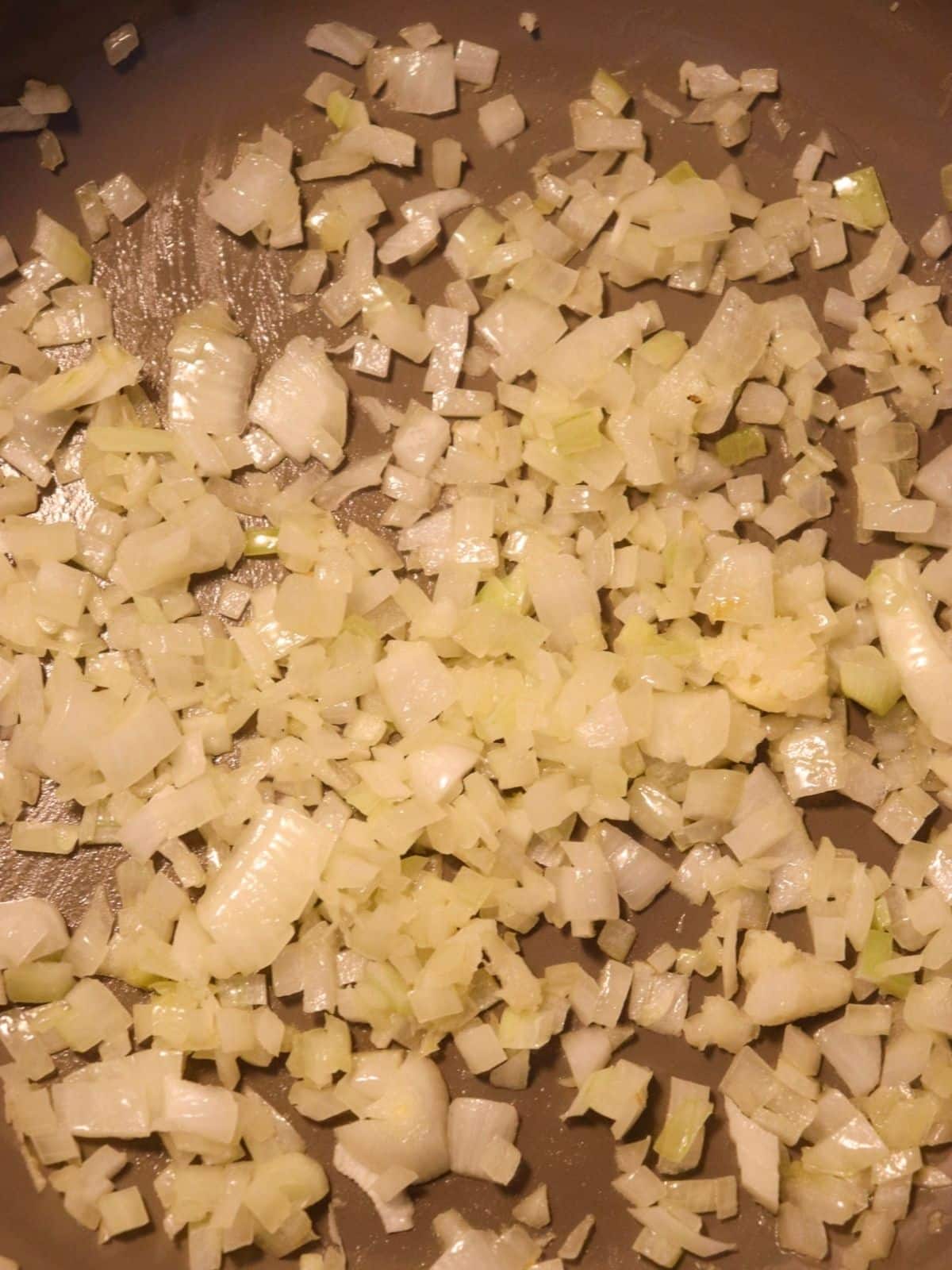 White onions sautéing in vegan butter in a skillet.
