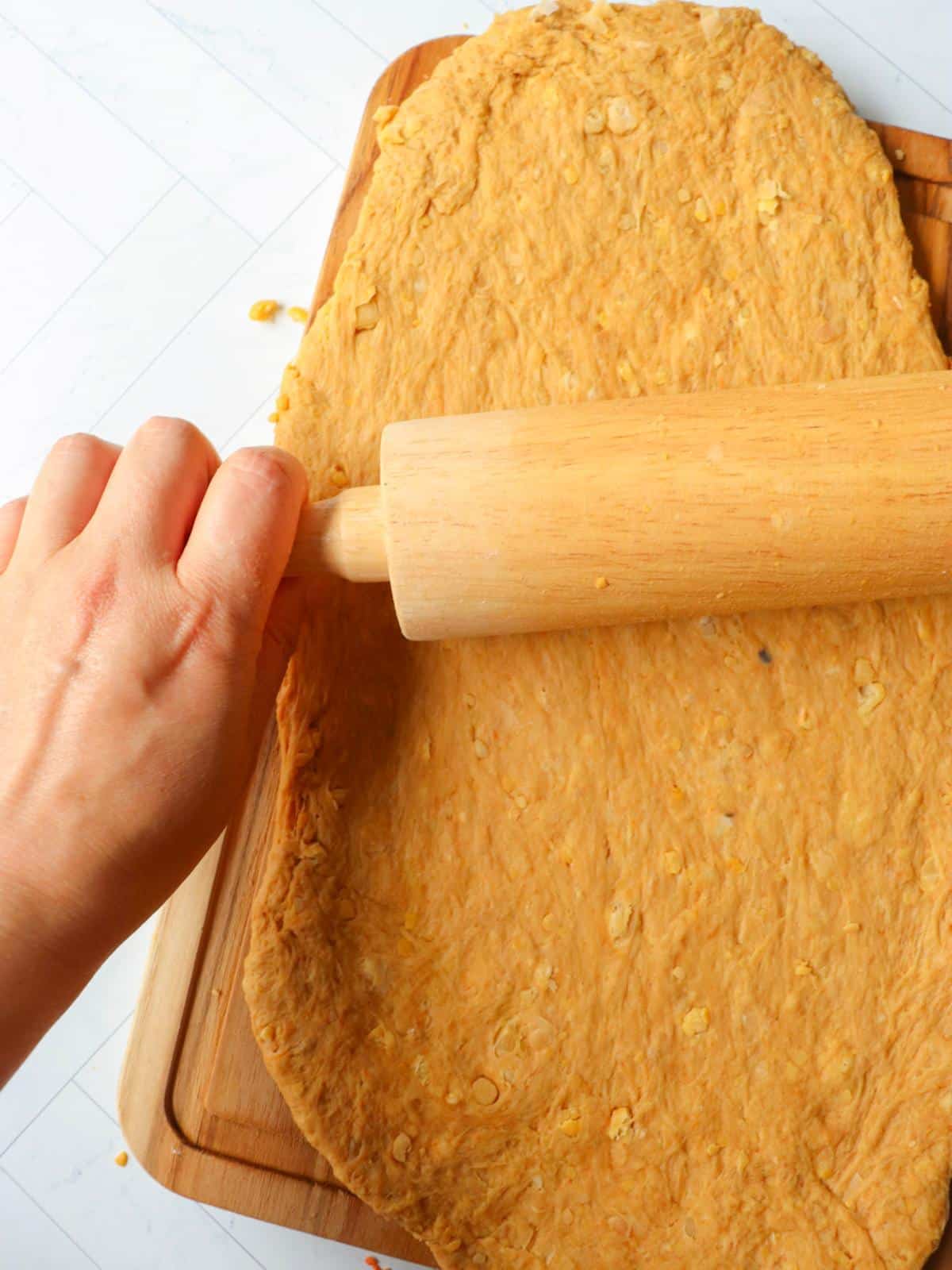 Hand and rolling pin rolling out seitan rib dough.