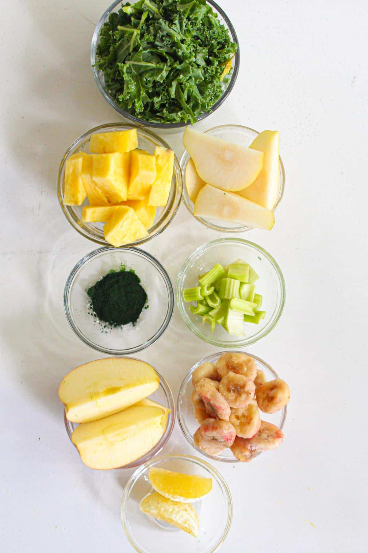 Ingredients for a spirulina smoothie laid out in individual small glass bowls.