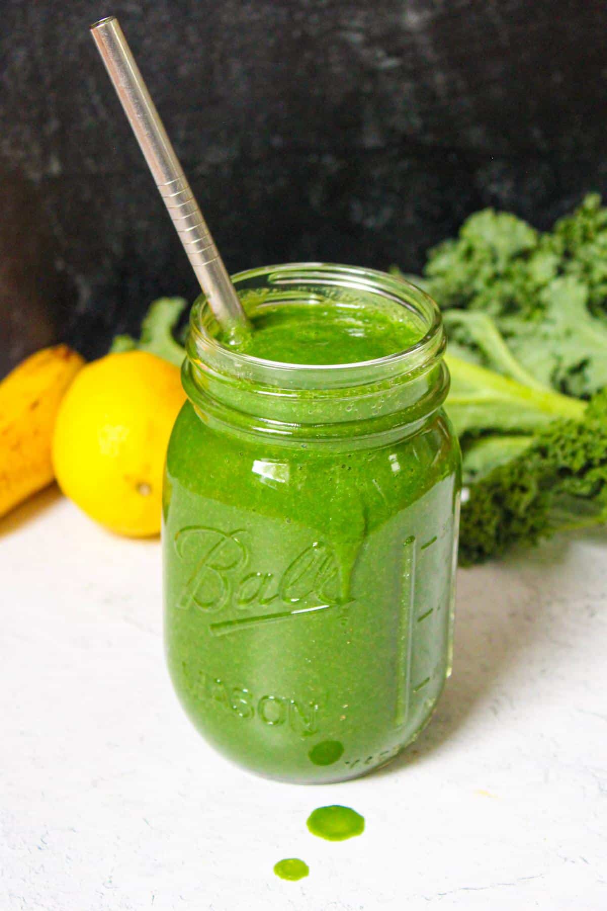 Glass mason jar filled with a green spirulina and pineapple kale smoothie