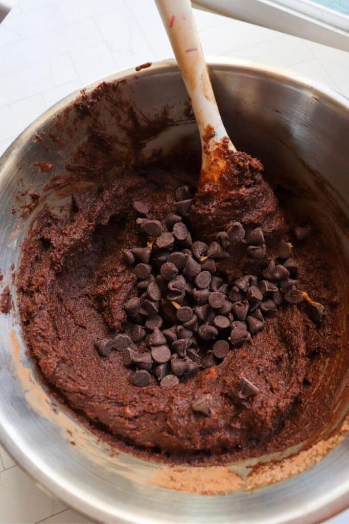 Sweet potato brownie batter in a mixing bowl with chocolate chips on top.