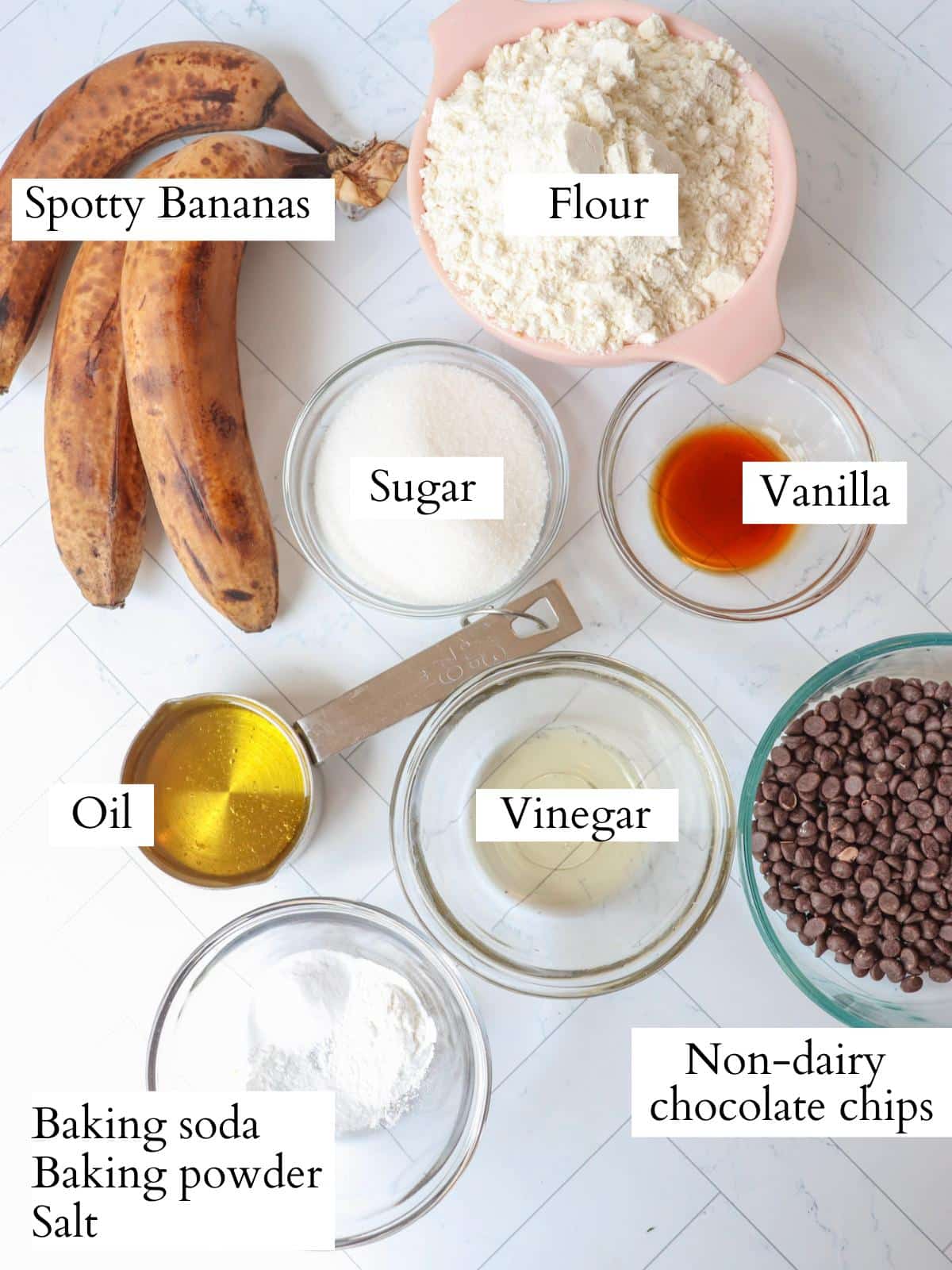 Ingredients for vegan banana bread laid out in small glass bowls on a counter.