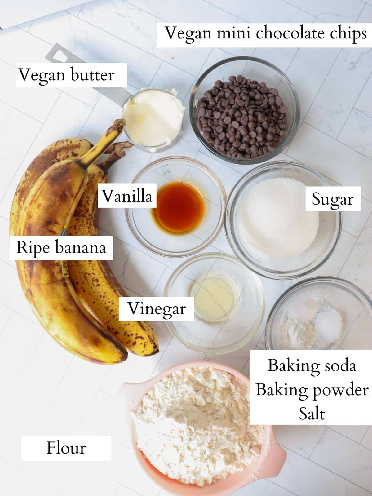Ingredients for vegan banana chocolate chip muffins laid out on a counter.