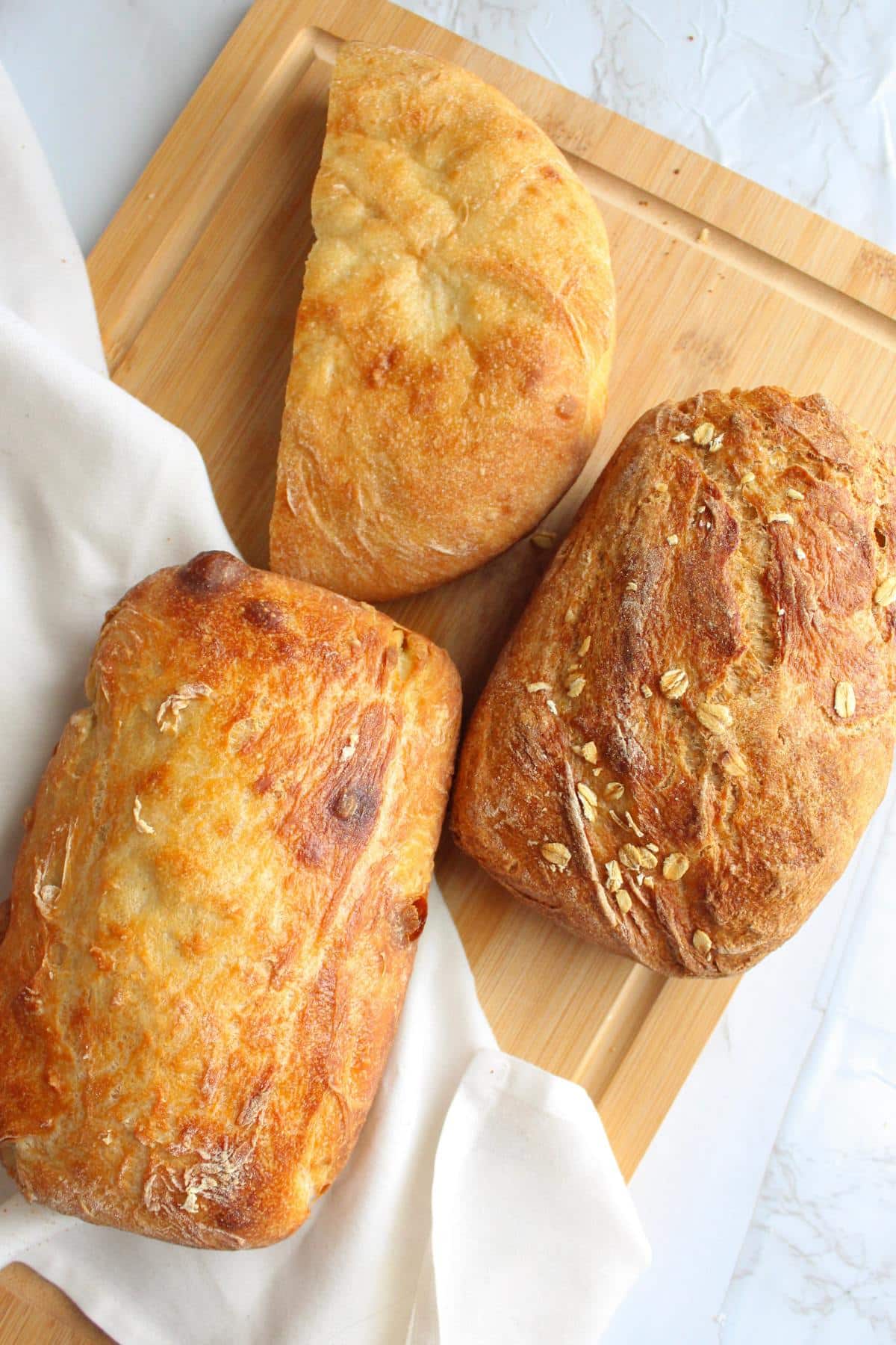 Three loaves of bread on a cutting board.