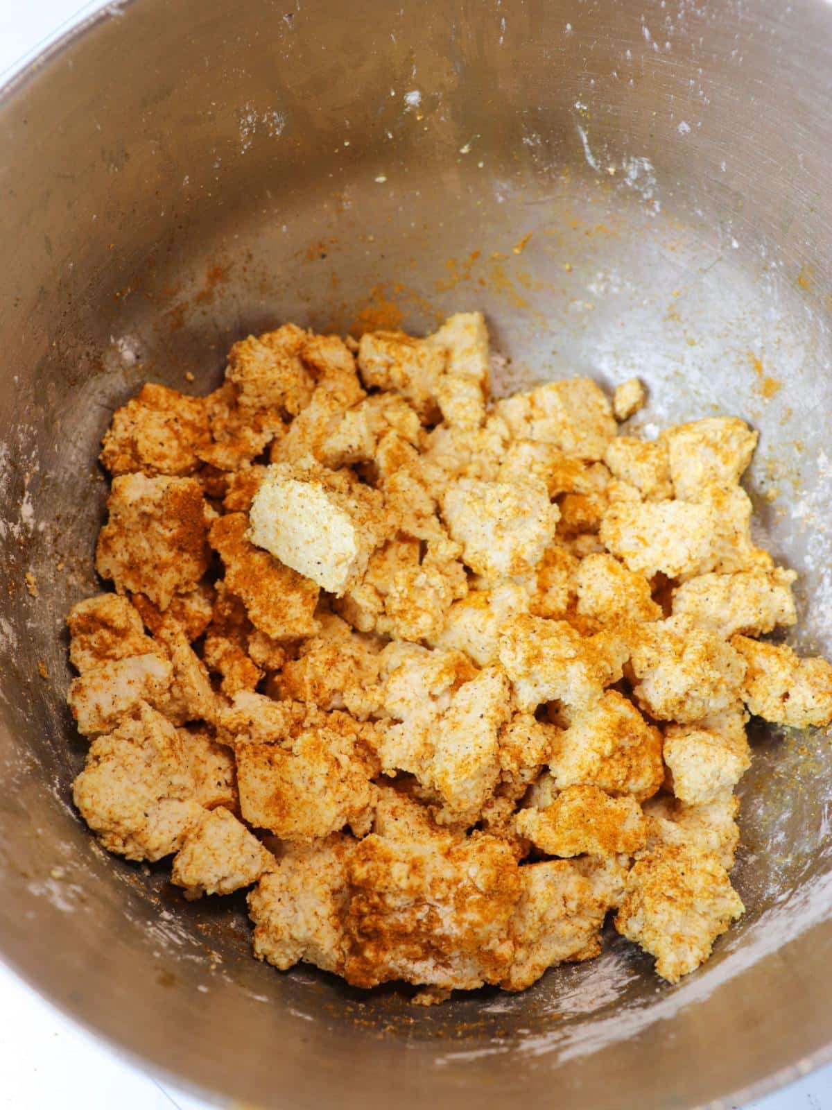 Tofu pieces in a mixing bowl with curry powder and corn starch.