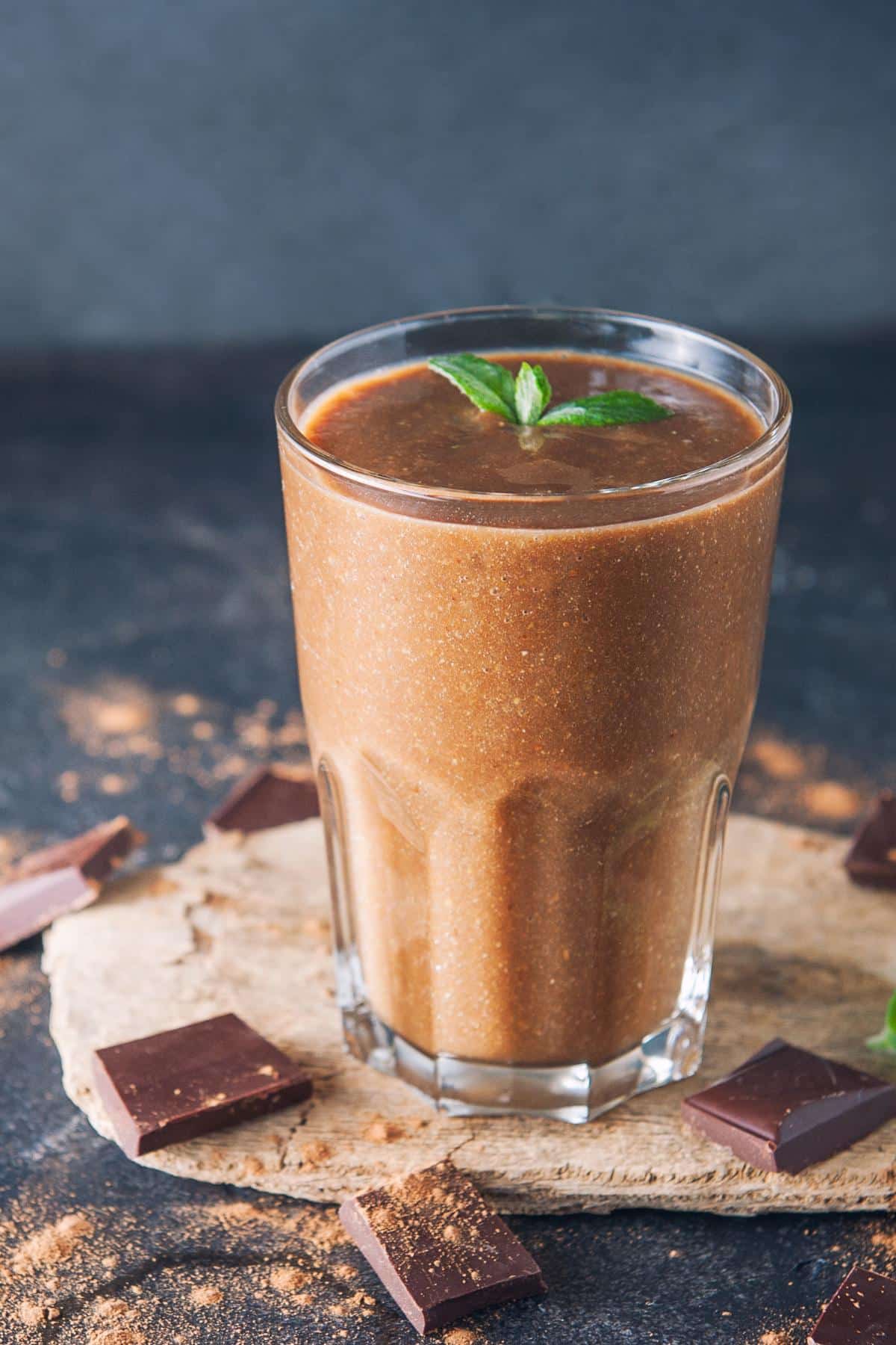Vegan thin mint smoothie in a glass next to small squares of dark chocolate.