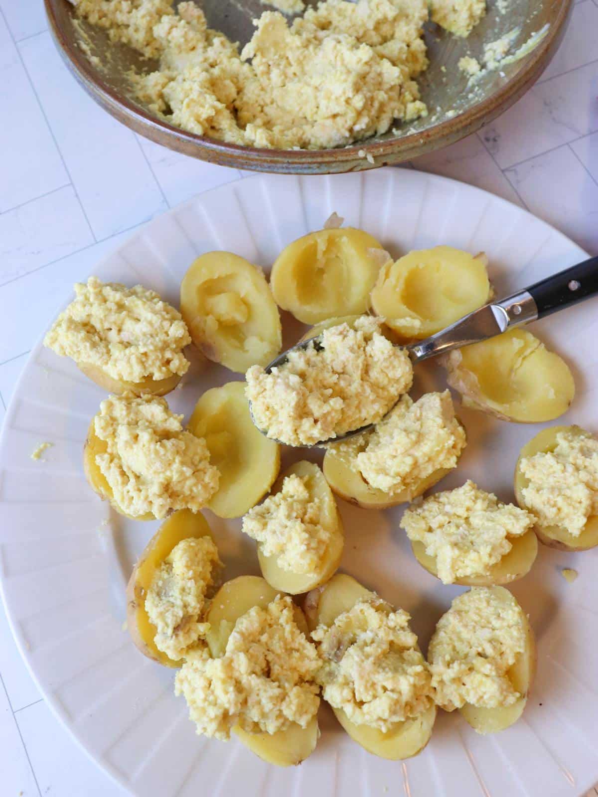 Small boiled potatoes being filled with vegan deviled egg filling.