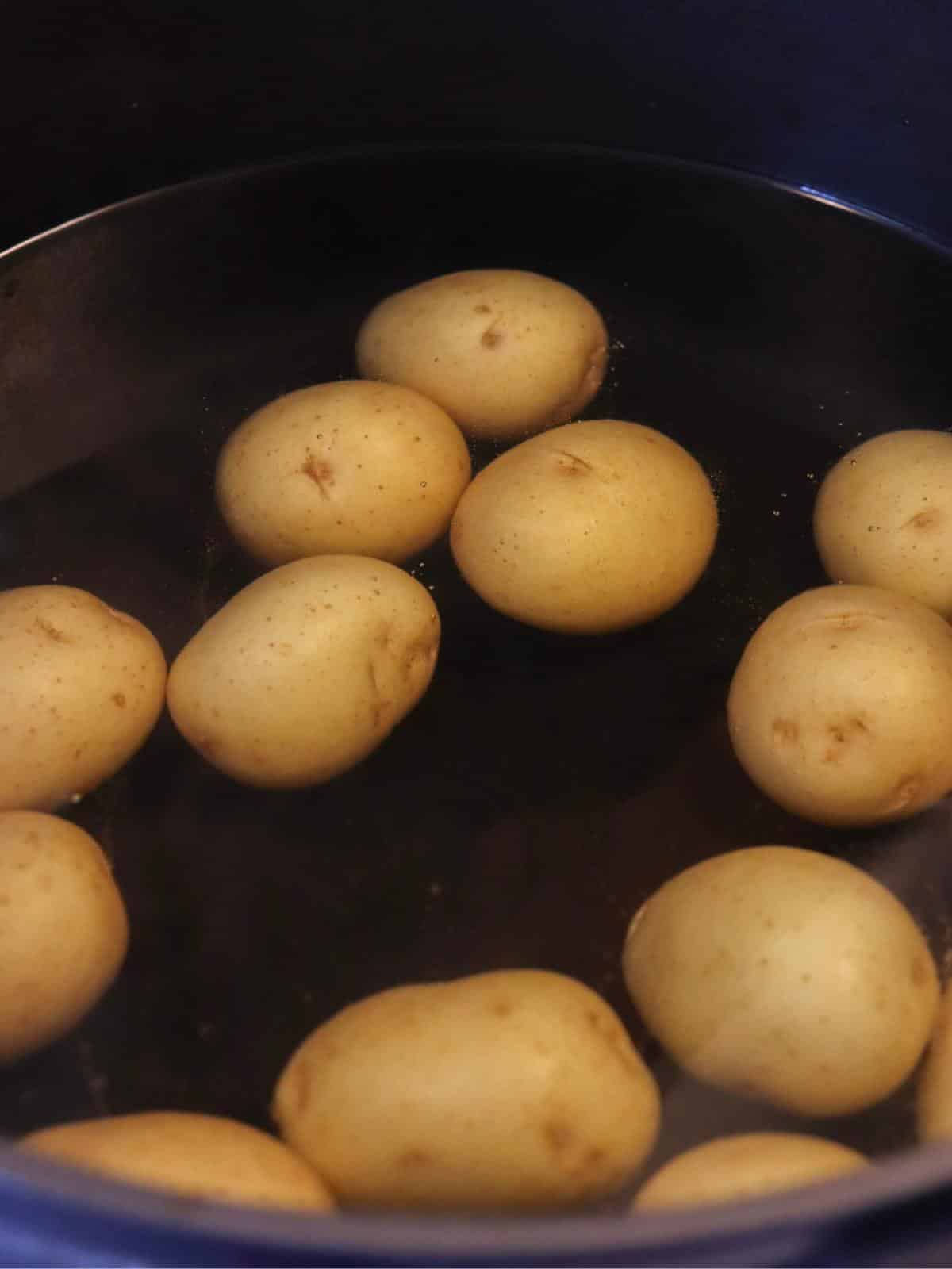 Small yellow potatoes boiling in a pot on the stove.