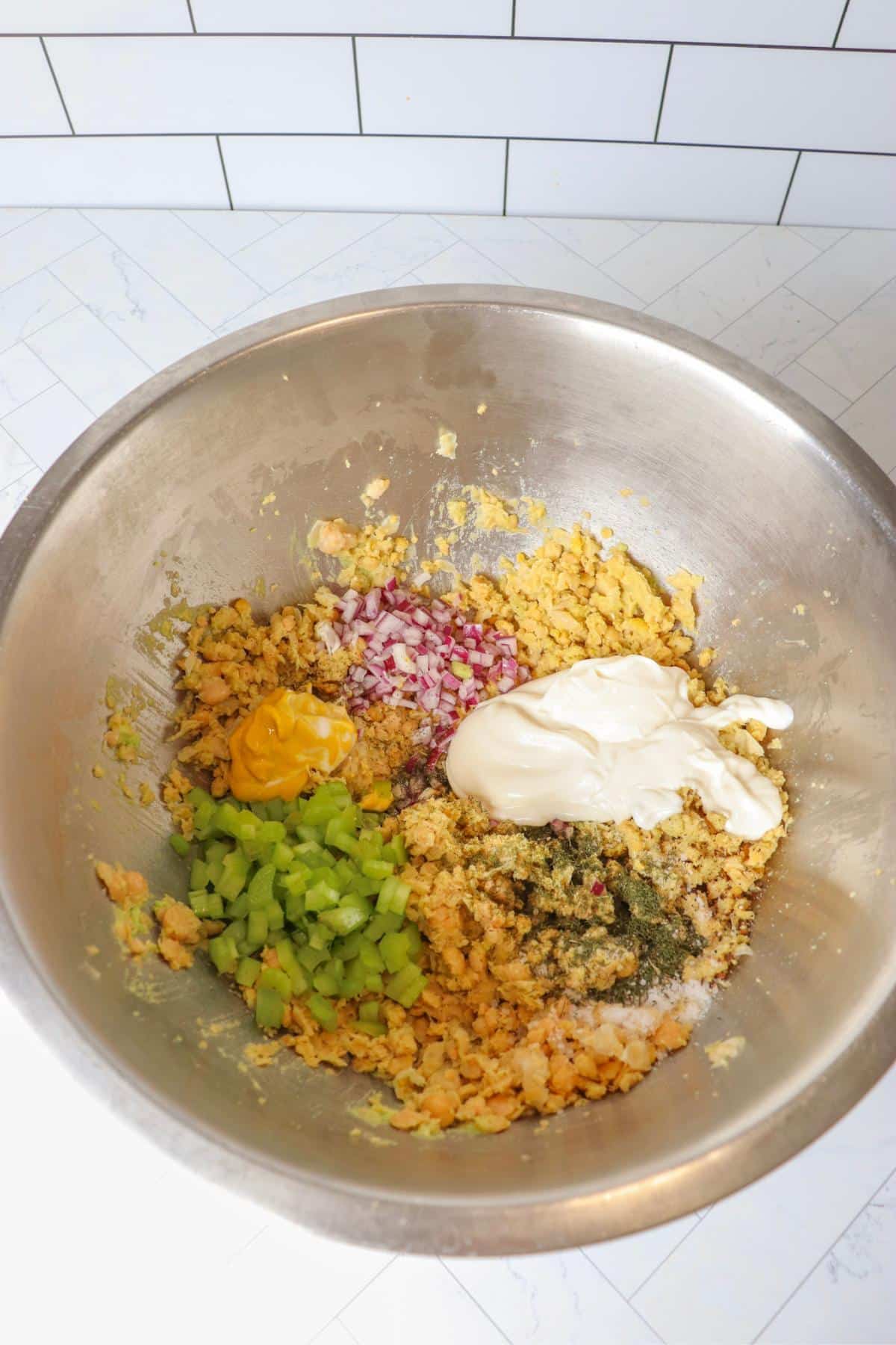 Chickpea salad sandwich ingredients in a mixing bowl before getting mixed
