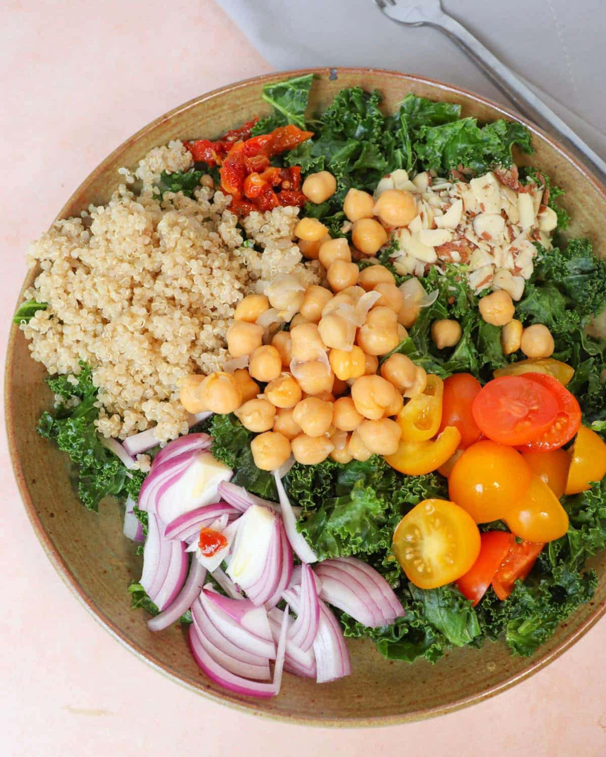 Kale quinoa salad in a bowl next to a fork and napkin.