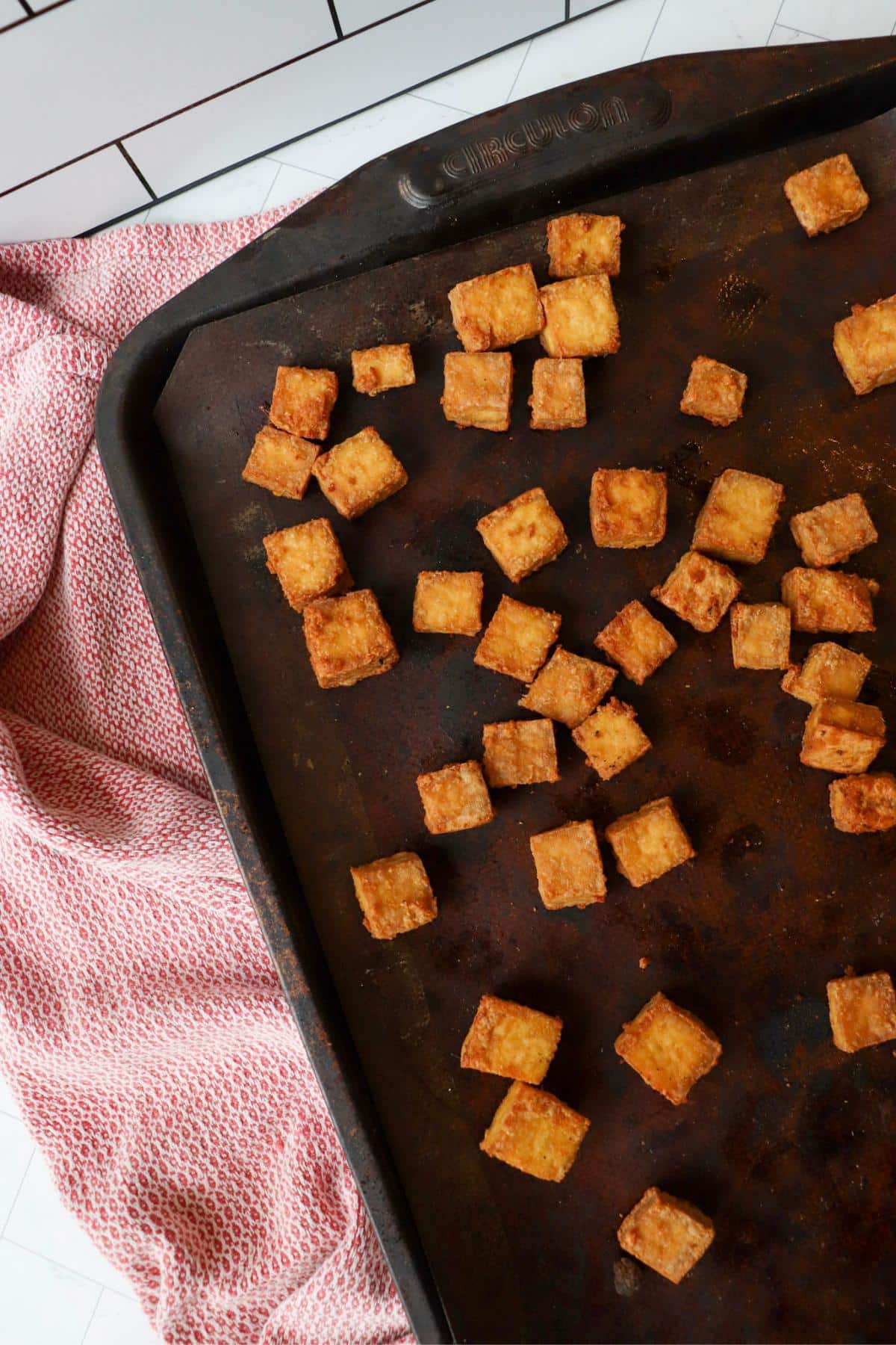 Baking sheet with crispy baked tofu cubes on it.