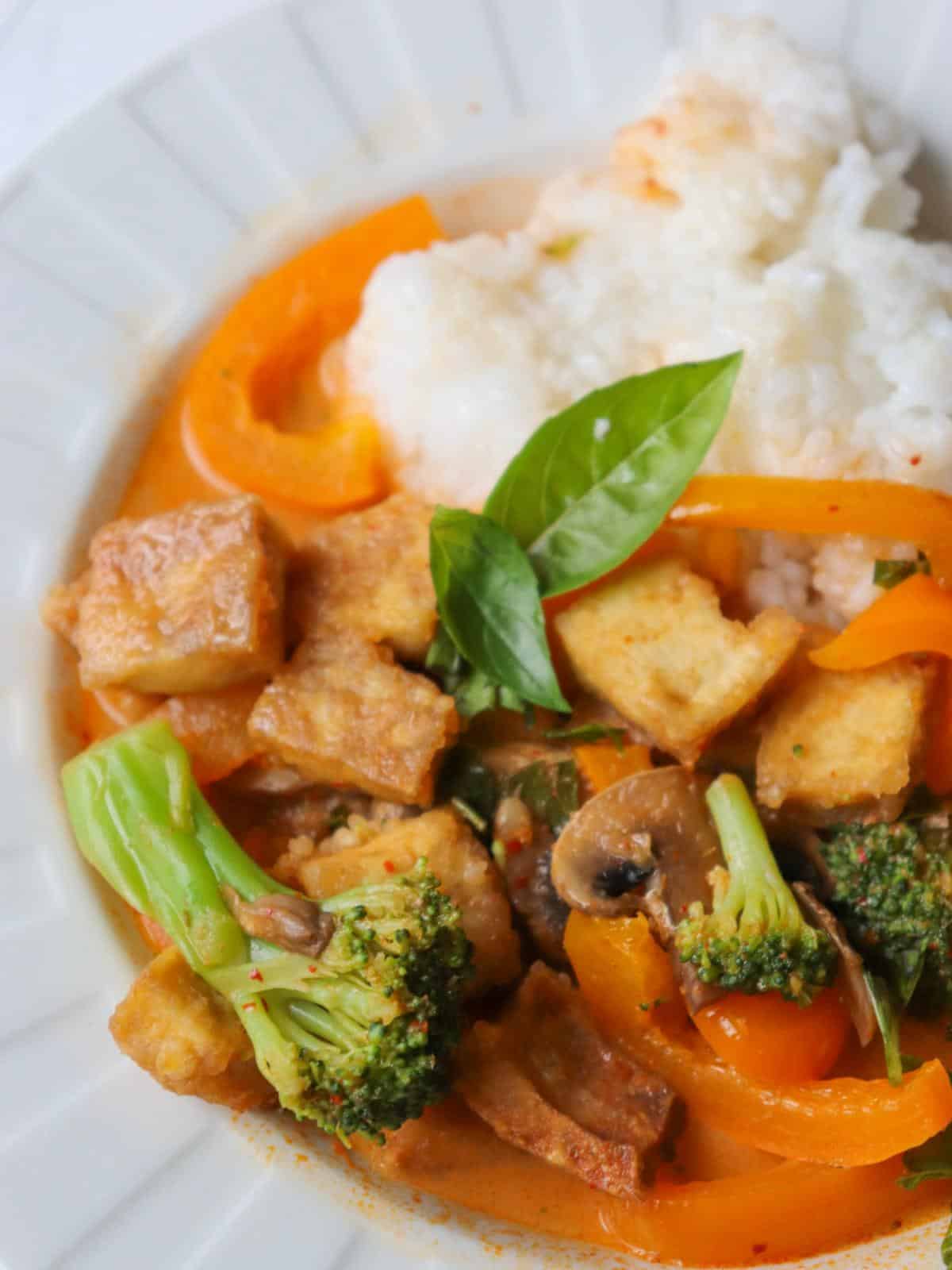 Vegan red thai tofu curry in a white bowl with white rice.