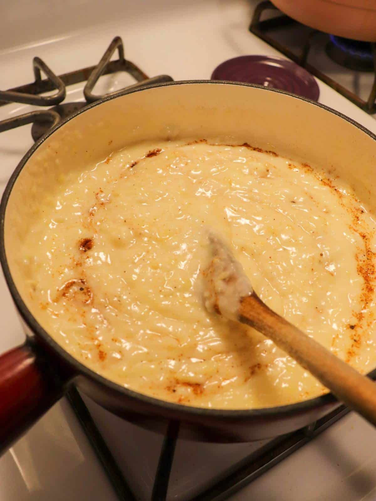 Vegan fondue on the stove with spices getting added in.