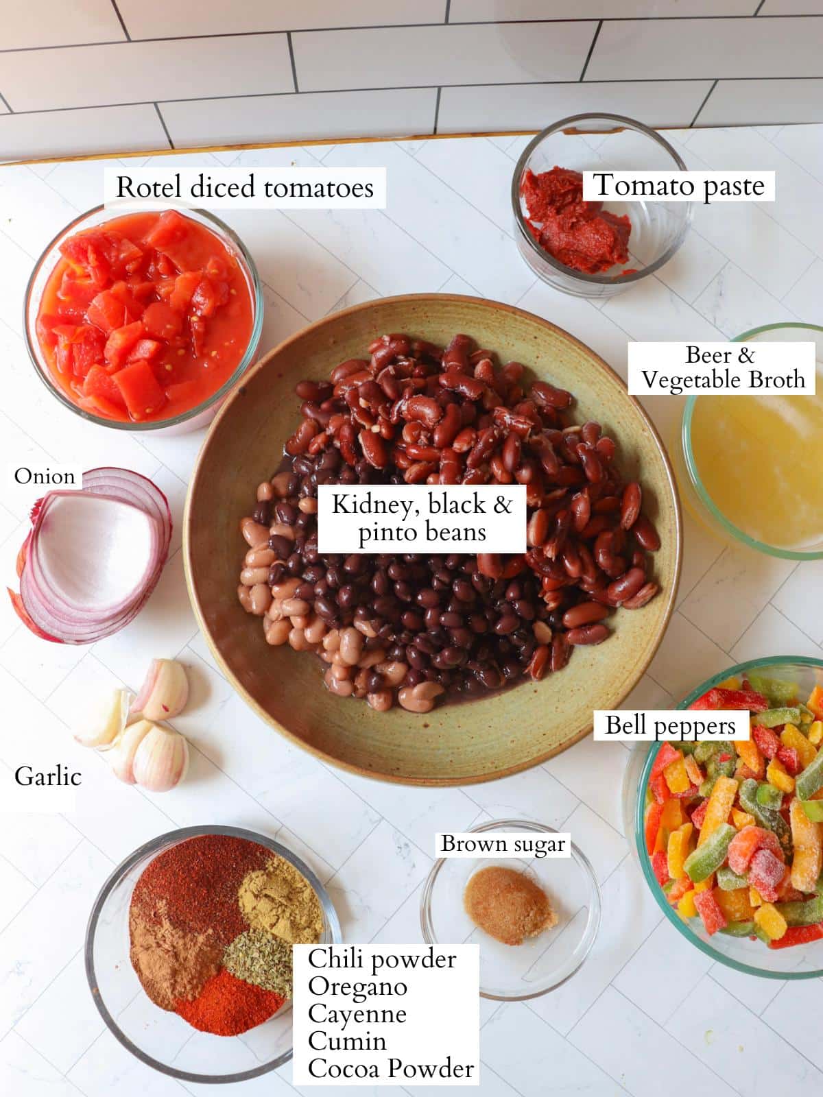 Ingredients for vegan three bean chili laid out in bowls on a kitchen counter.