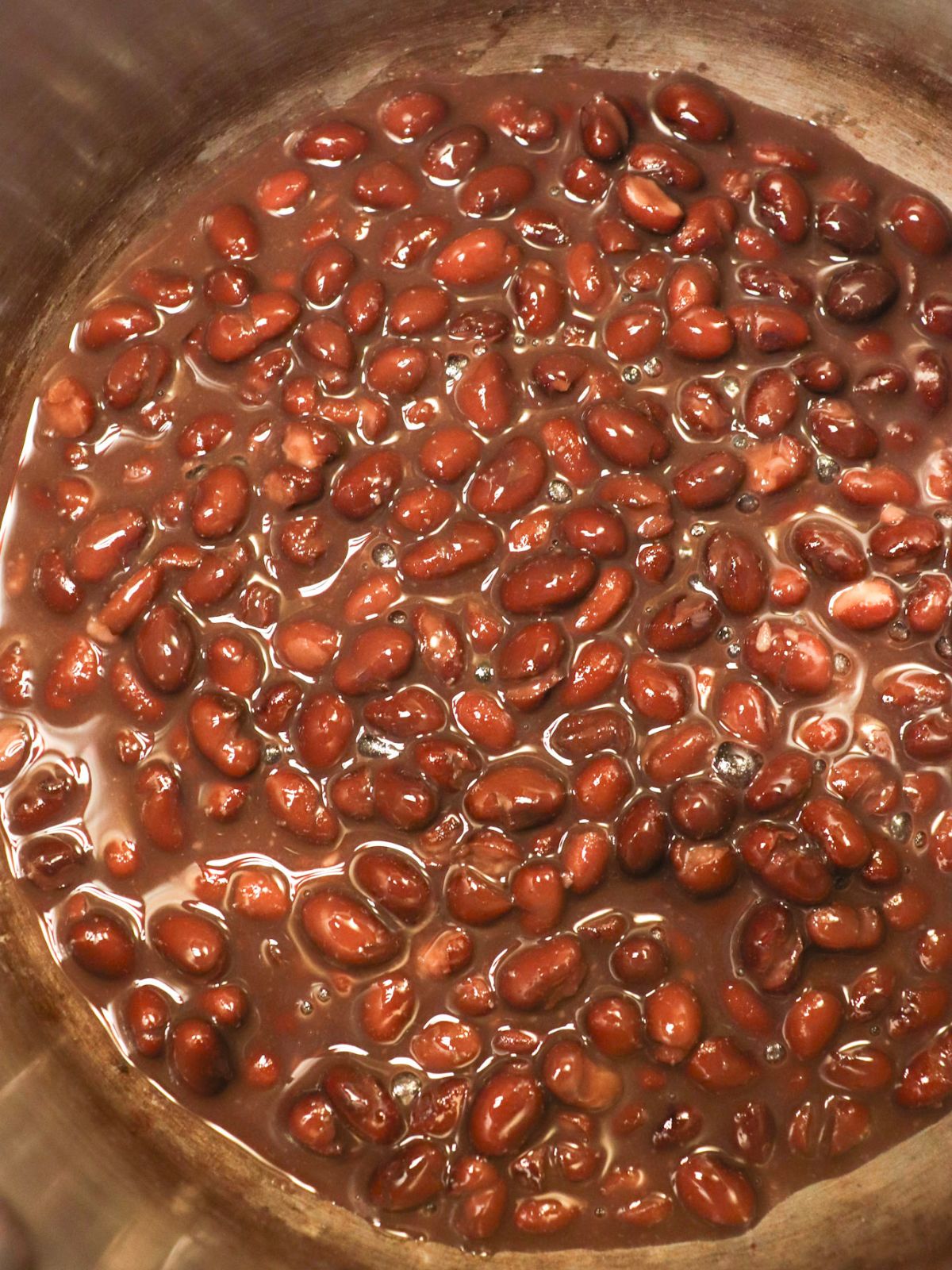 Black beans warming up in a pan on a stove.