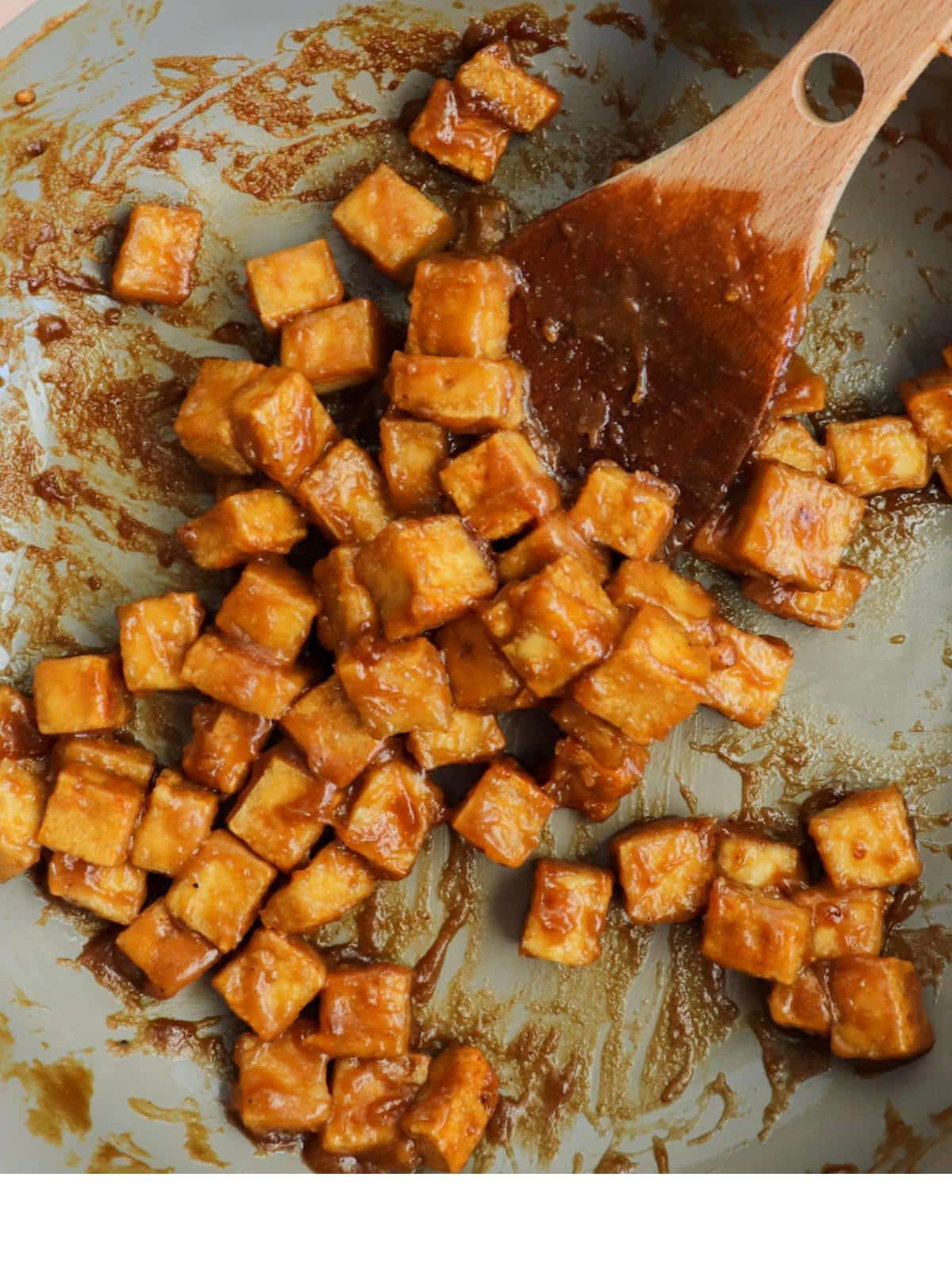 Crispy tofu cubes in a pan after adding sauce.
