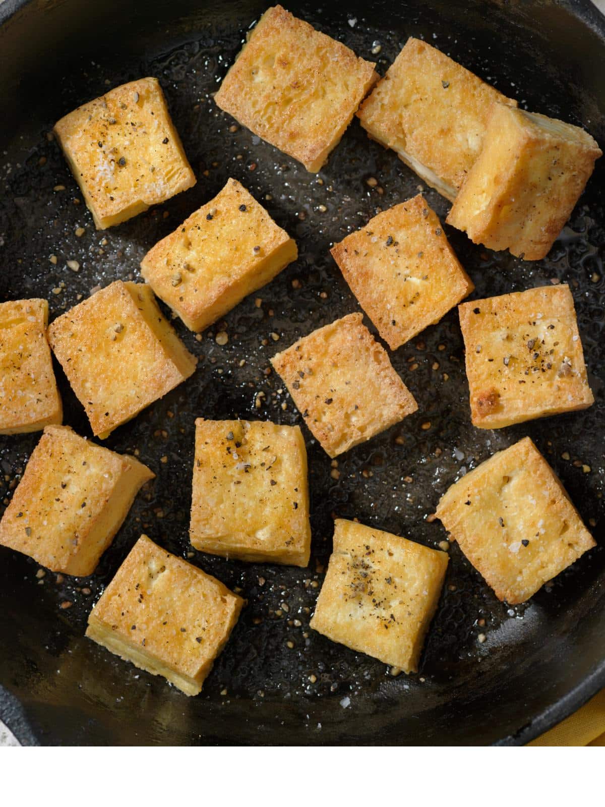 Crispy pan fried tofu in a cast iron skillet.