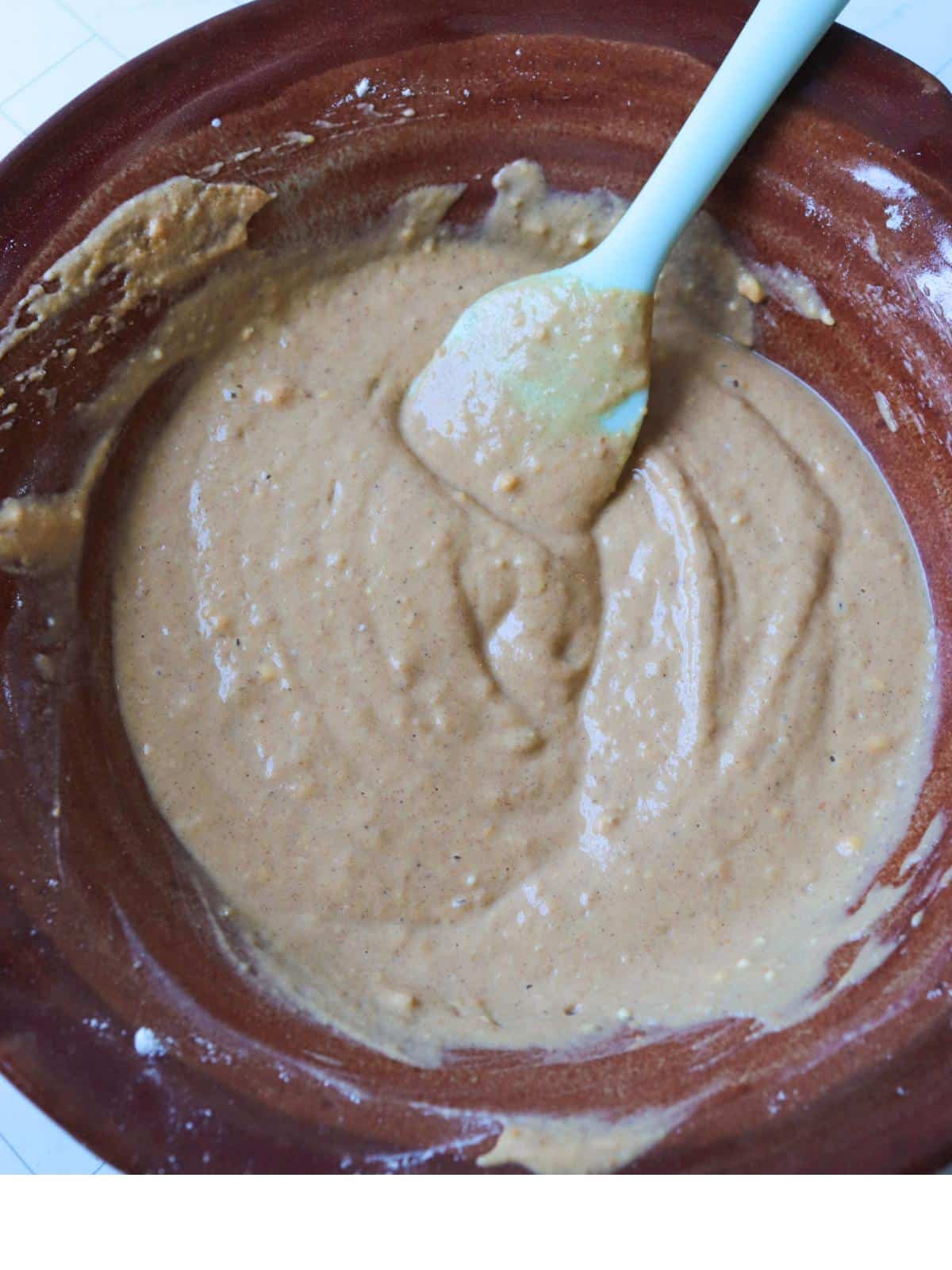 Vegan pumpkin spice pancake batter in a mixing bowl with a rubber spatula.